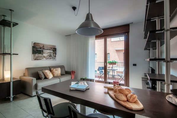 A modern living space with a sofa, dining table, and a view of the outside balcony.