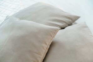 A close-up of two beige pillows on a bed.