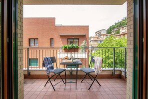 A balcony with two chairs, a small table, and a potted plant.