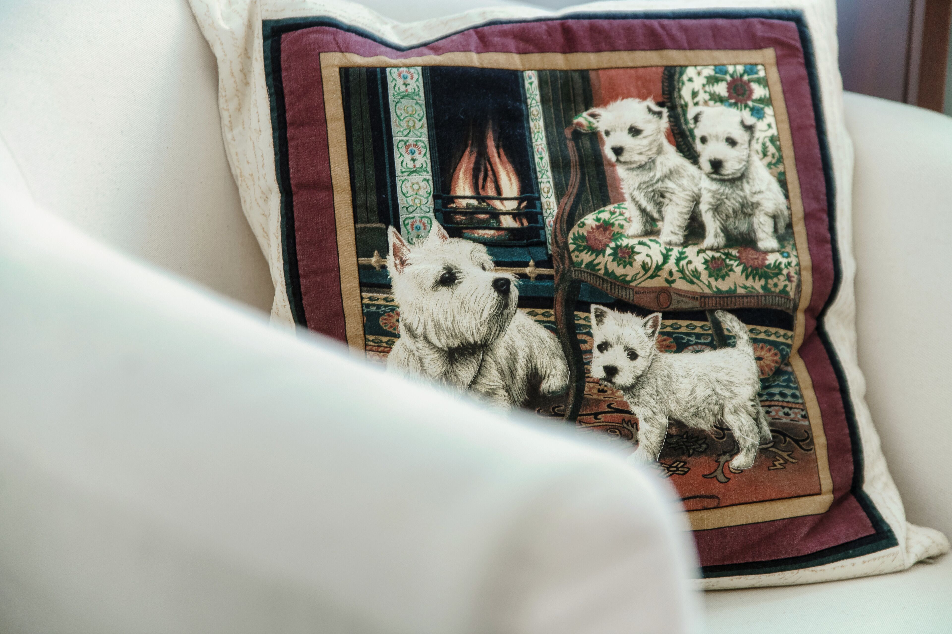 Een kussen met een gedetailleerde print van drie honden en een open haard.