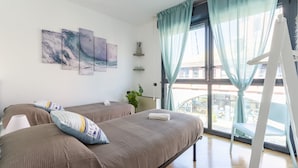 Habitación de hotel con dos camas, un ventanal con cortinas, una planta y una obra de arte en la pared.