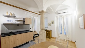A modern kitchen with wooden cabinets, a black countertop, and a central island. - JOIVY Cute Flat Near The Aquarium (Genoa)