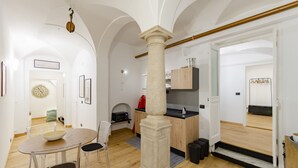 A modern kitchen with a wooden countertop, a stone column, and a dining area with a glass table and chairs. - JOIVY Cute Flat Near The Aquarium (Genoa)