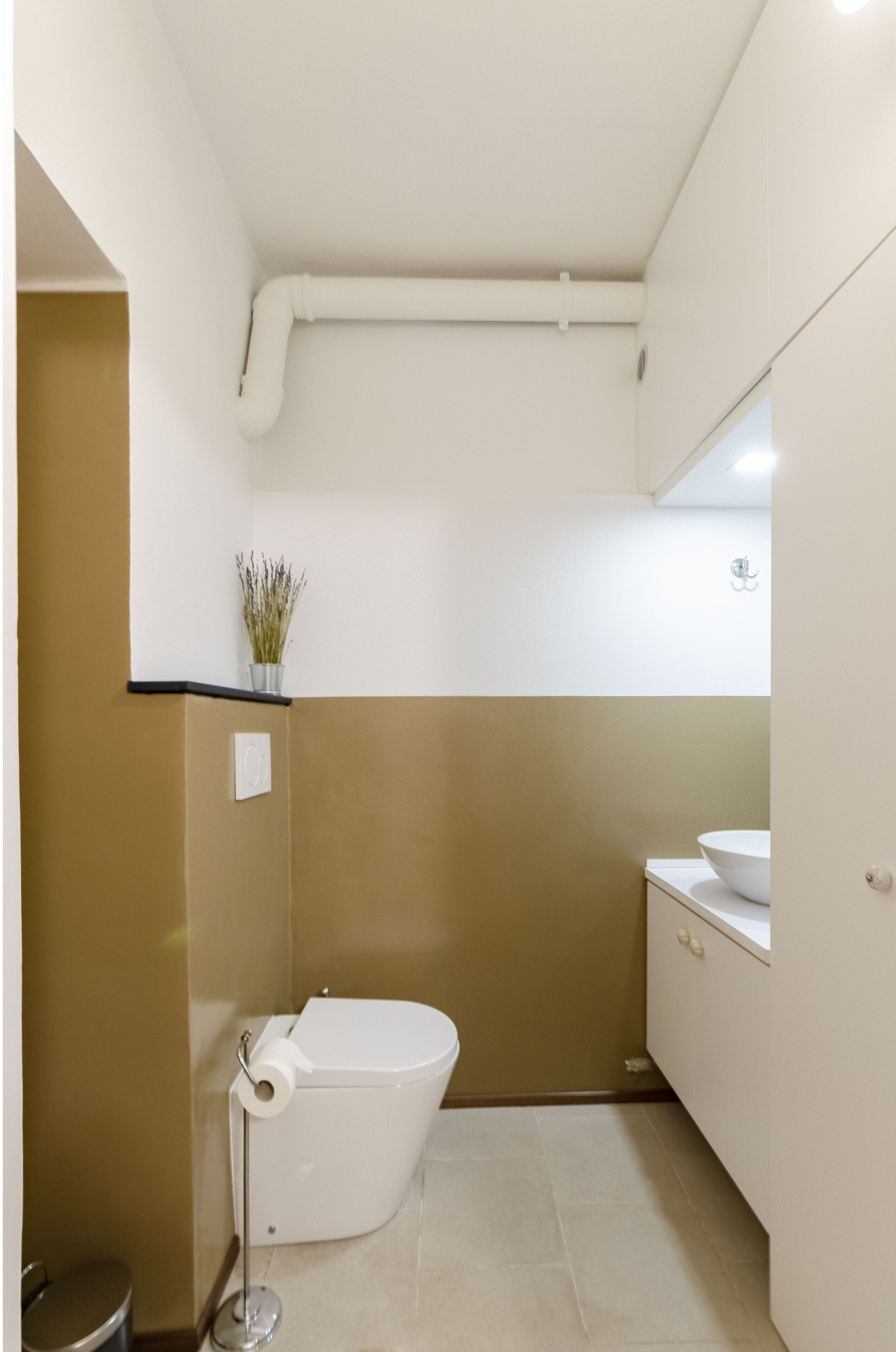 Un baño pequeño y funcional con inodoro, lavamanos y un cubo de basura.