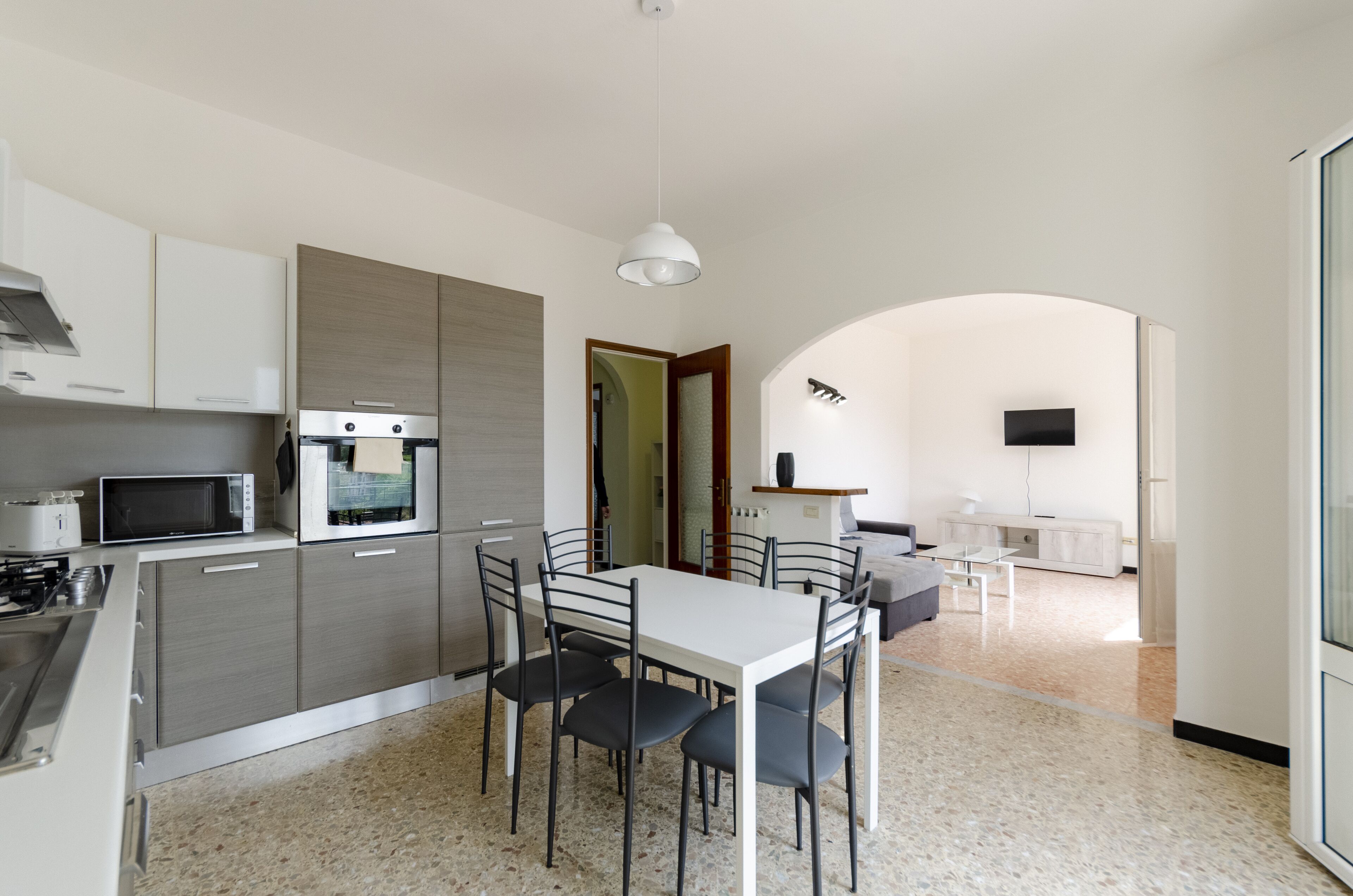 A modern kitchen with a dining area, featuring a microwave, oven, and a dining table with chairs.