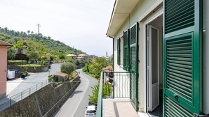 Een balkon met uitzicht op een kronkelende weg en gebouwen op een heuvel.