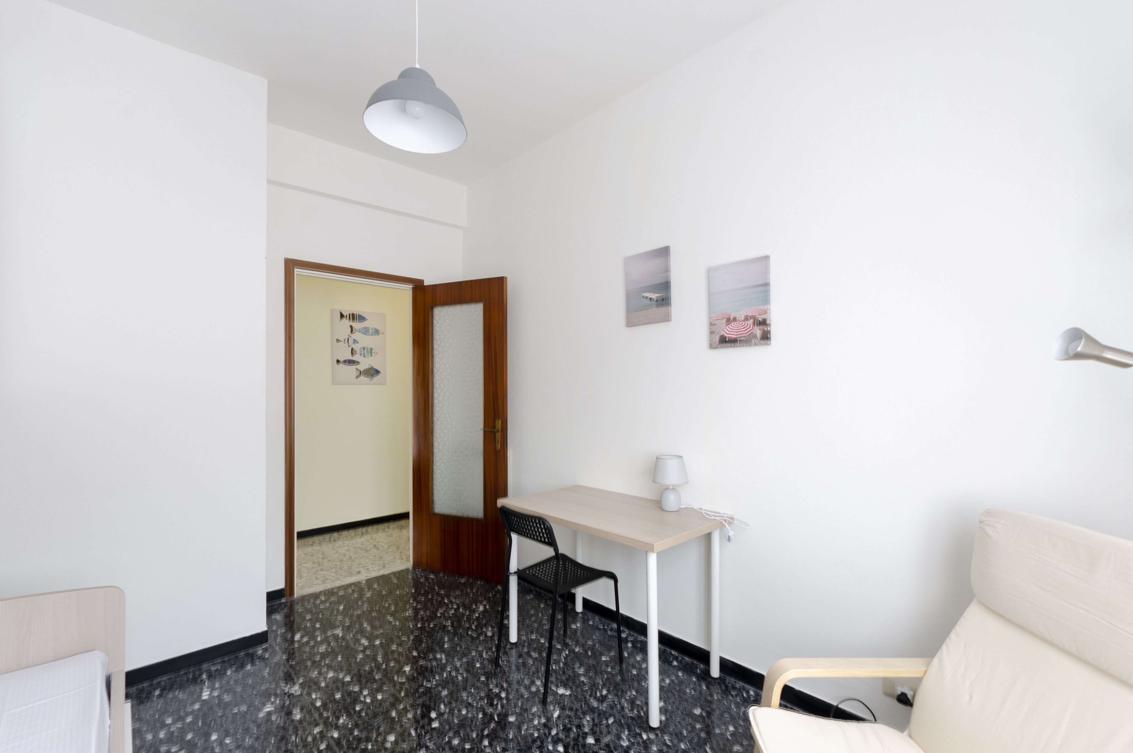 Une chambre d’hôtel équipée d’un lit, d’un bureau, d’une chaise, d’une lampe et d’un téléviseur fixé au mur.