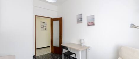 Une chambre d’hôtel équipée d’un lit, d’un bureau, d’une chaise, d’une lampe et d’un téléviseur fixé au mur.