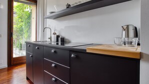 A modern kitchen with a black countertop, stainless steel appliances, and a wooden cutting board. - JOIVY Superb Studio In The Centre Of Milan (Milan)