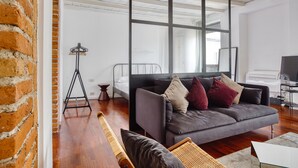 A modern living room with a grey sofa, a wooden floor, and a large window. - JOIVY Superb Studio In The Centre Of Milan (Milan)