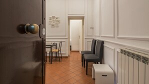 A hallway with a dining area, chairs, a radiator, and a door with a handle. - JOIVY Trevi Fountain's relais (Rome)
