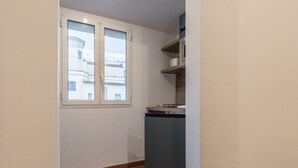A compact kitchen with a window, a built-in oven, and a small cabinet. - JOIVY Trevi Fountain's relais (Rome)