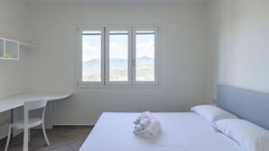 Una camera d'albergo con un letto, una scrivania e una finestra vista montagne.