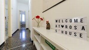 A hallway with a welcome sign, a cat figurine, and a vase with flowers.