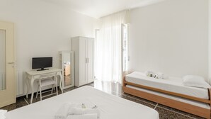 A hotel room with a bed, a desk with a television, a wardrobe, and a bathroom visible through a door.