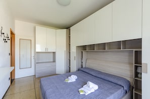 A modern bedroom with a bed, built-in wardrobe, and a bedside table.