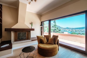 Relax in a spacious living room with a panoramic city view, a plush sofa, and a cozy fireplace.