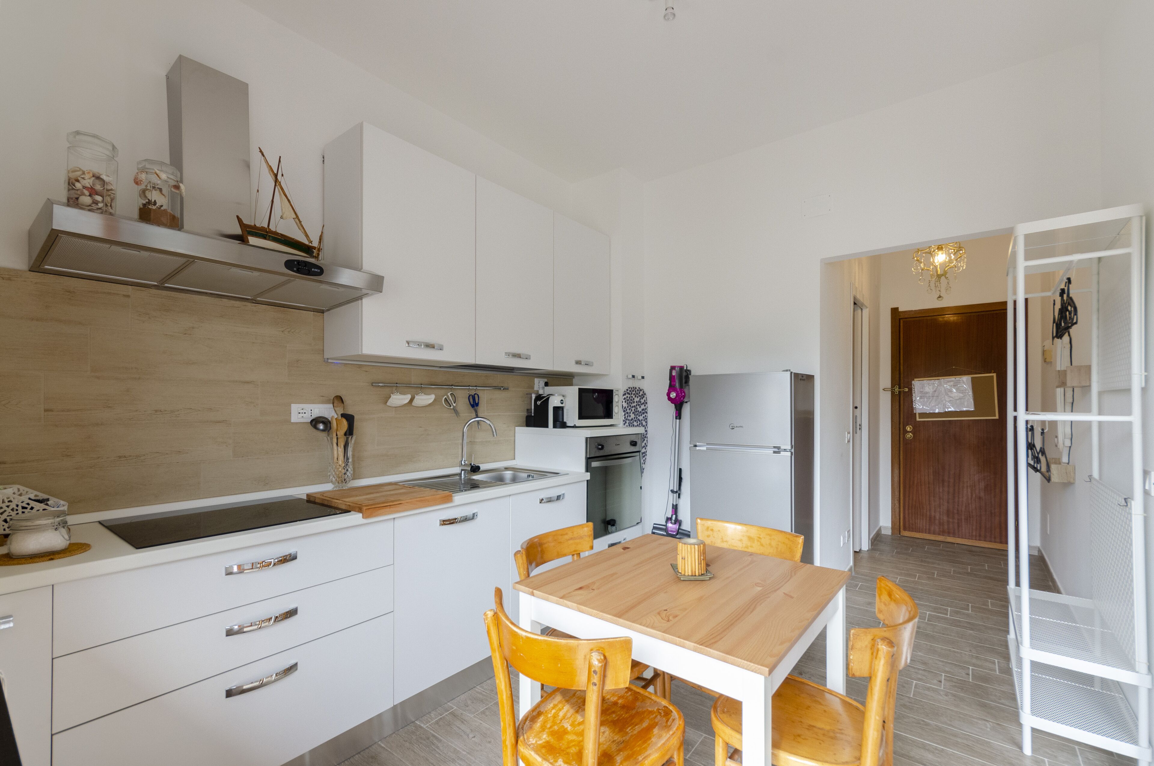 Una cocina moderna con armarios blancos, una mesa de comedor de madera y un microondas.