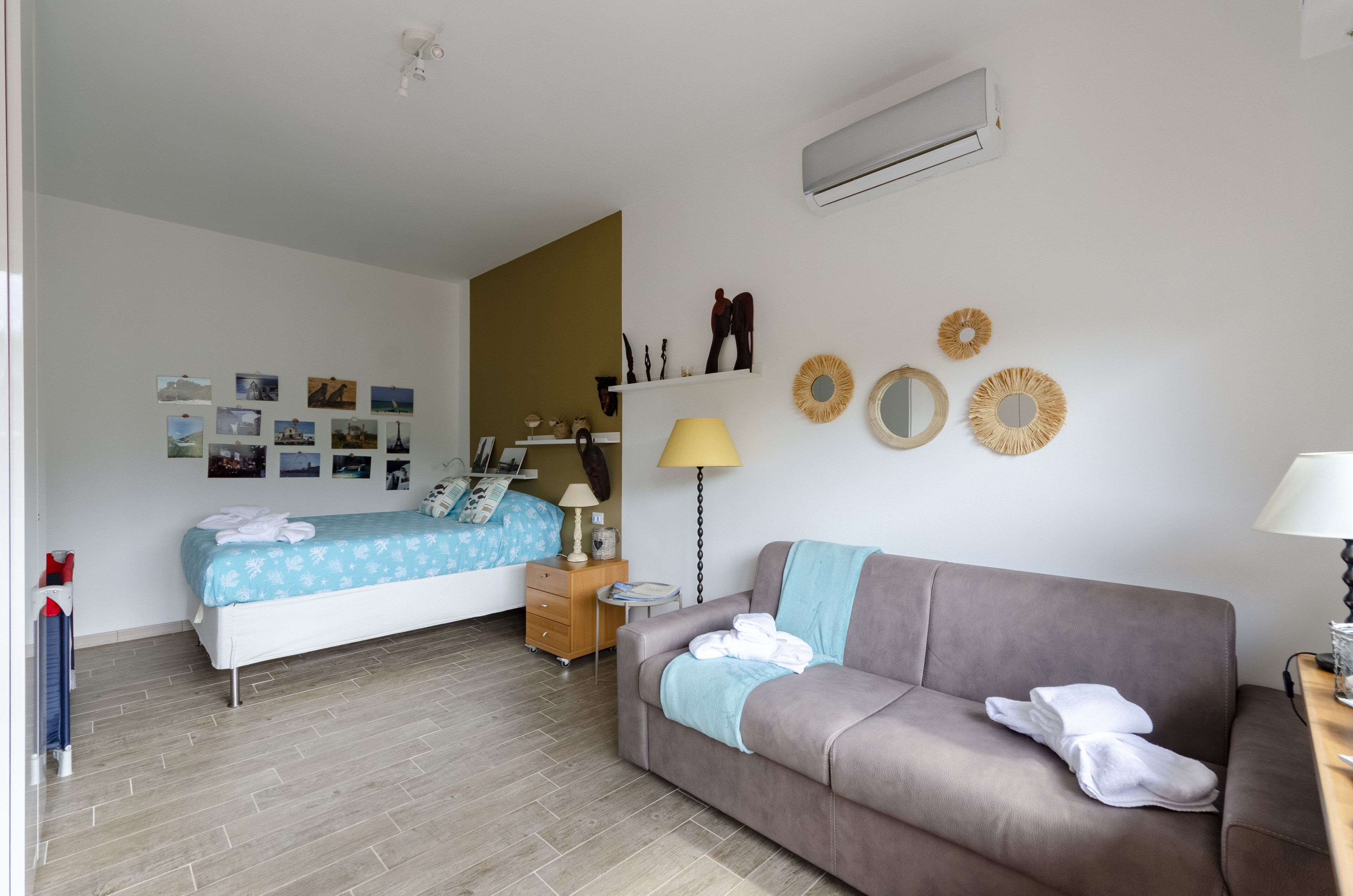 A bedroom with a bed, a sofa, a nightstand, a lamp, and wall decorations.