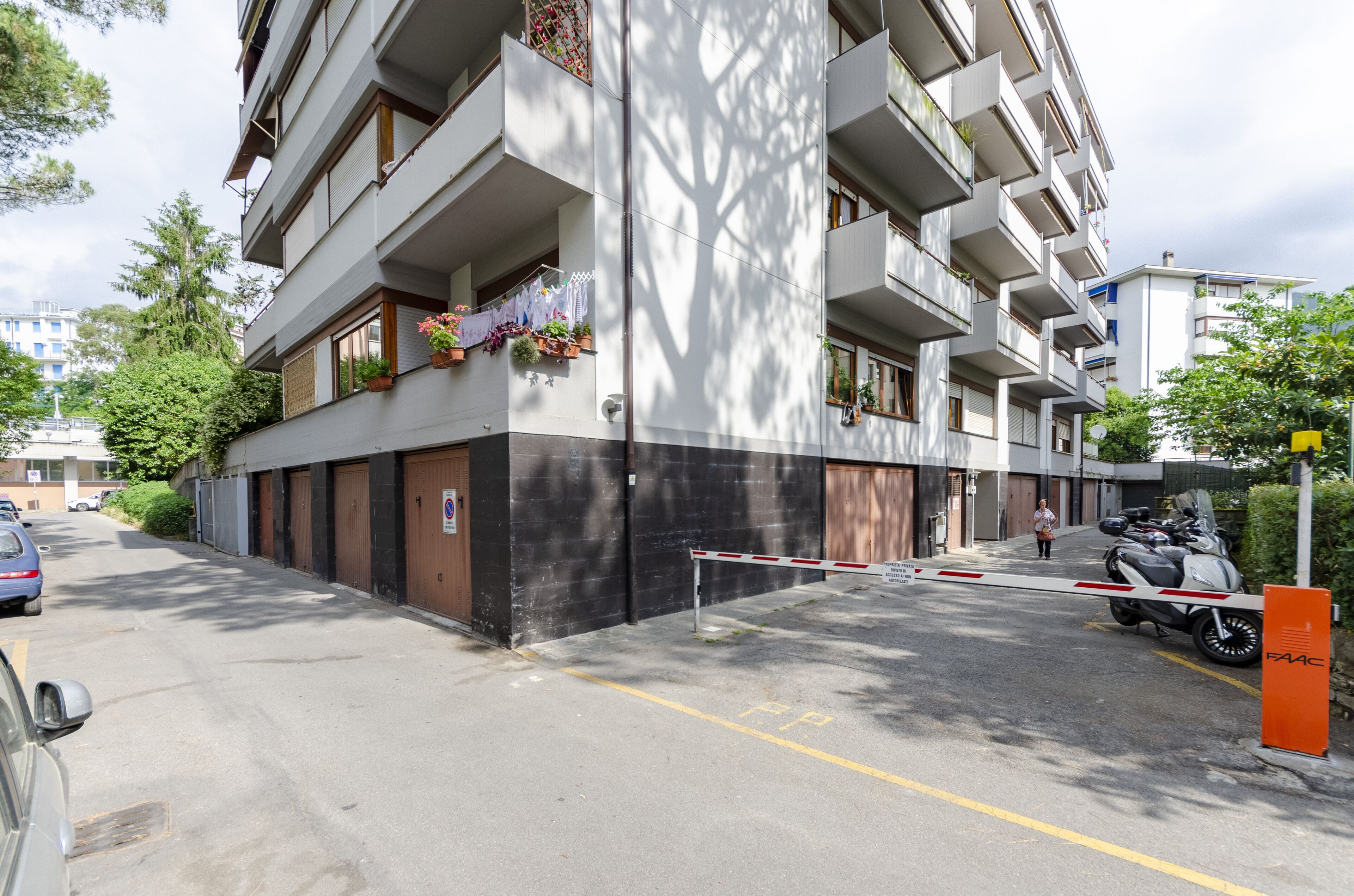 A multi-story residential building with balconies, a gated entrance, and a parked motorcycle.