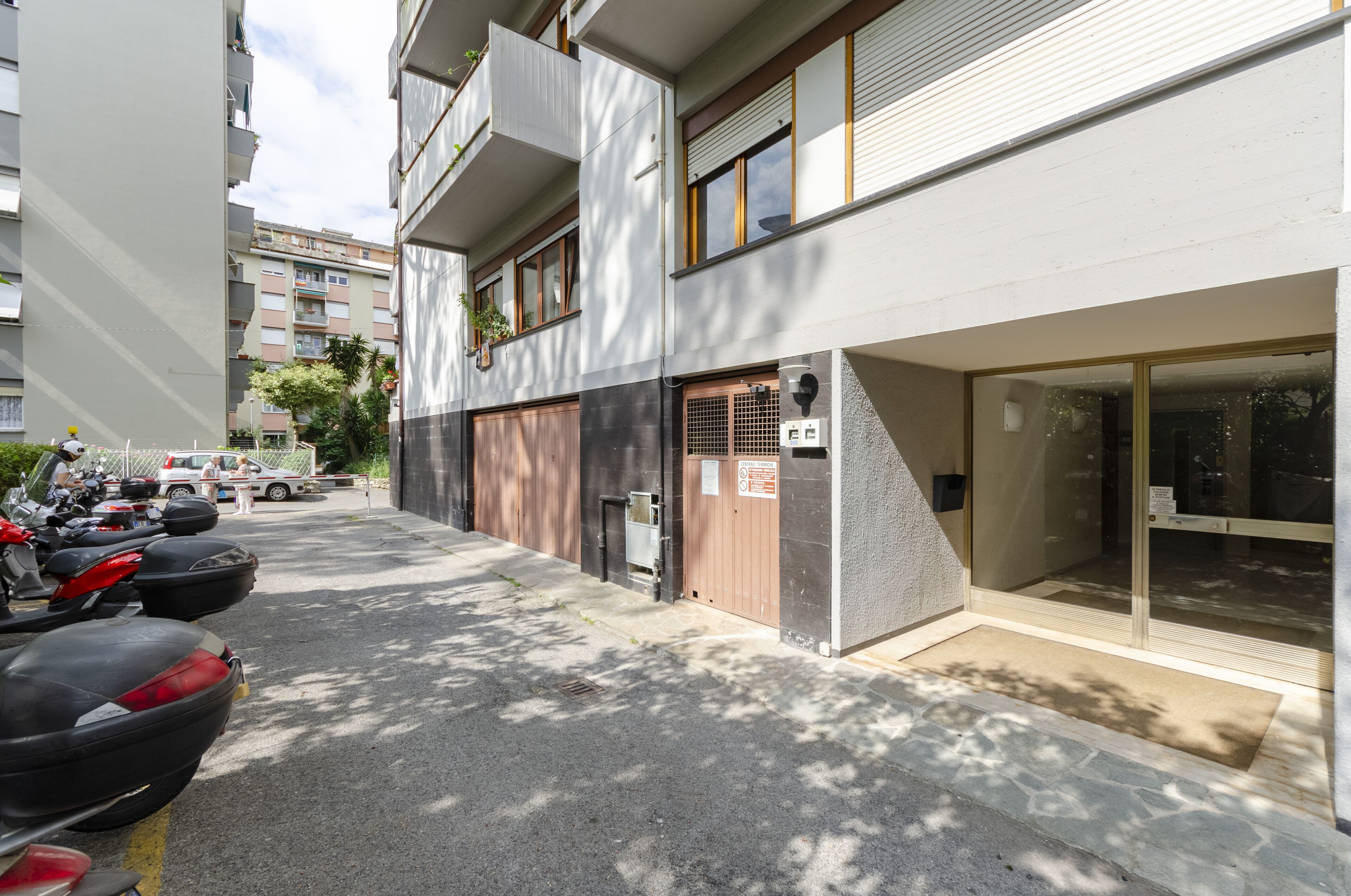 A modern building with a parking area, a gated entrance, and a visible signboard.