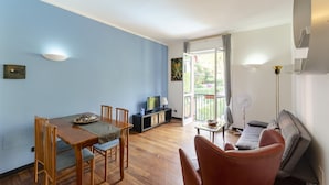 A modern living room with a dining area, a sofa, and a TV.