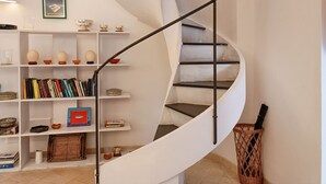 Eine Wendeltreppe mit Metallgeländer, weißen Wänden und Regalen mit verschiedenen Dekorationsgegenständen und Büchern.