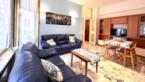 A living room with a blue sofa, a small table, and a TV in the background.