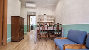 Ein schmaler Flur mit einem Holzschrank, einem Esstisch mit Stühlen und einem blauen Sofa.