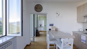 Eine moderne Küche mit Holzarbeitsplatte, weißen Stühlen und Blick durch ein großes Fenster.