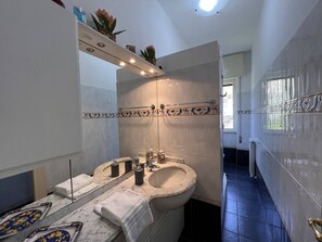 A modern bathroom with a large mirror, a marble sink, and a towel rack.