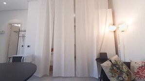 Ein Hotelzimmer mit einem Bett, einem Schreibtisch, einem Stuhl, einer Lampe und einem Vorhang.