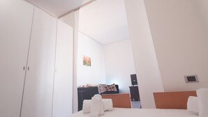Ein Hotelzimmer mit einem Bett, einem Kleiderschrank, einem Schreibtisch und einem kleinen Fernseher.
