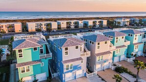 Zona residencial costeira com edifícios de vários andares, alguns com varandas, e uma praia ao fundo.