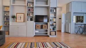 Una sala de estar con un sofá, una televisión y una estantería.