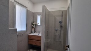 Un baño moderno con cabina de ducha de vidrio, tocador de madera y un espejo grande.
