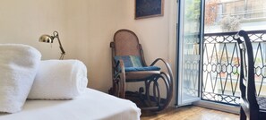 Ein Zimmer mit einem Bett, einem Sessel, einer Lampe und Blick durch eine Glastür.