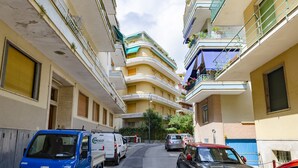 Una calle estrecha con coches aparcados y una furgoneta azul.