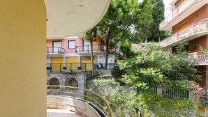 Un patio con muro de piedra, un pequeño puente y un edificio con balcones.