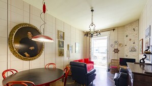 Un comedor con una mesa redonda y sillas rojas, un sofá negro y una lámpara roja.