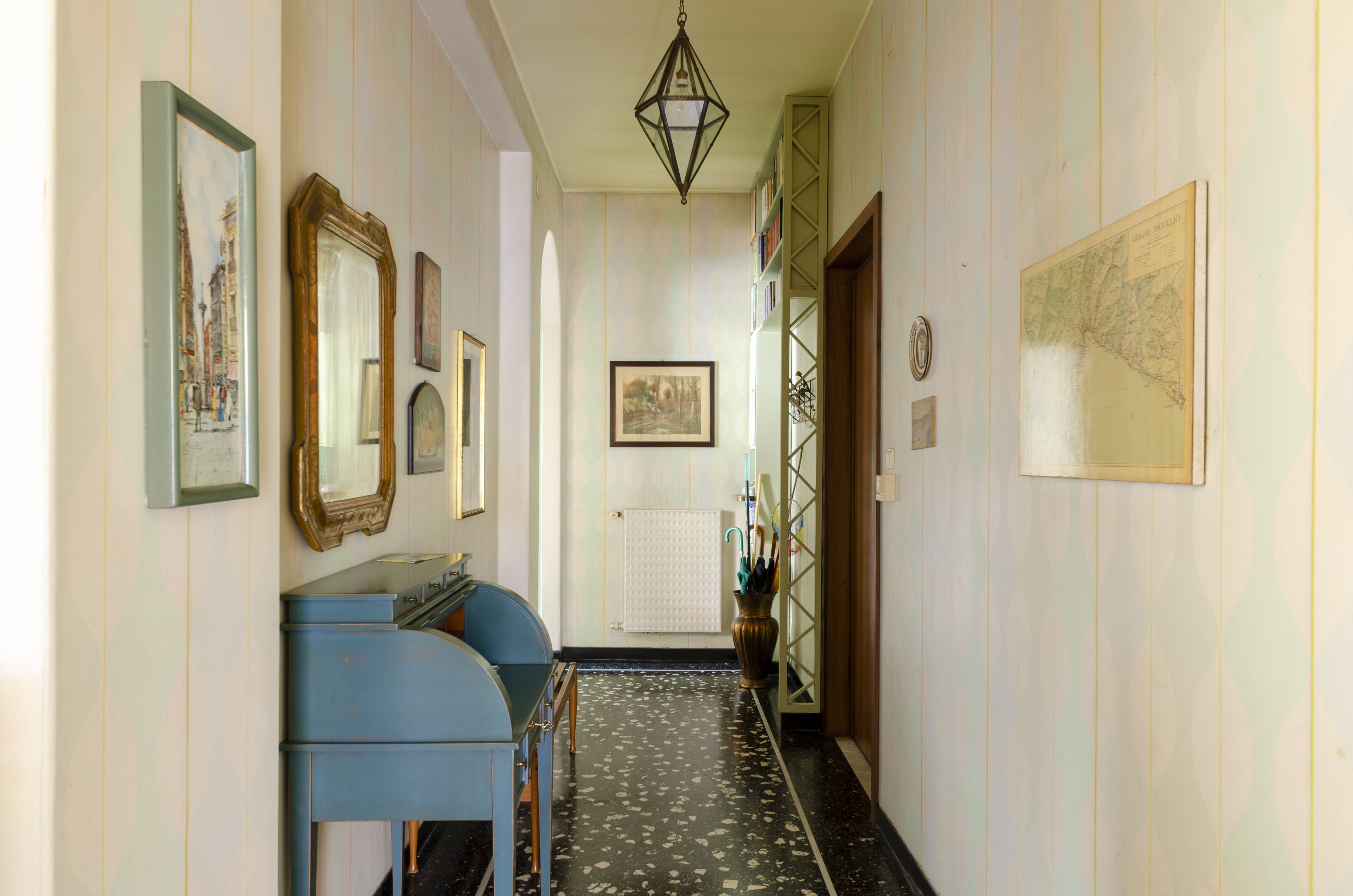 A hallway with framed artwork, a blue cabinet, and a map on the wall.