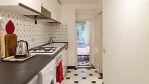 A compact kitchen with a gas stove, a kettle, and a coffee maker on the counter. - JOIVY Flat By The Sea Promenade (Camogli)