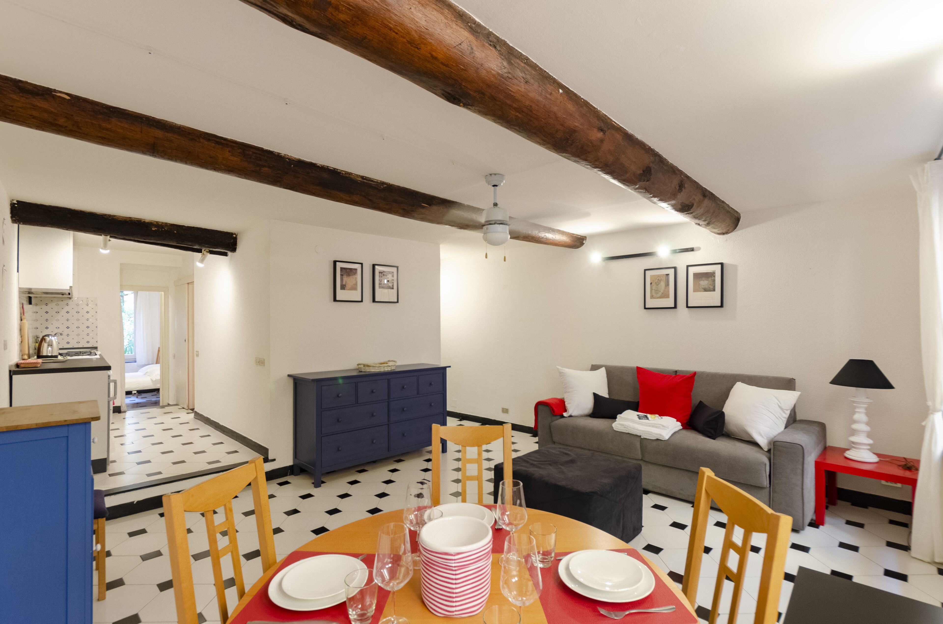 A dining area with a table set for four, a sofa, a blue cabinet, and a ceiling fan.