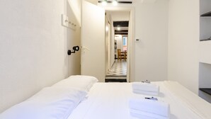 A hotel room with a bed, a desk, and a chair. There is a door leading to another room. - JOIVY Flat By The Sea Promenade (Camogli)