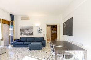 Uma sala de estar moderna com um sofá, uma mesa de jantar e uma estante de livros.