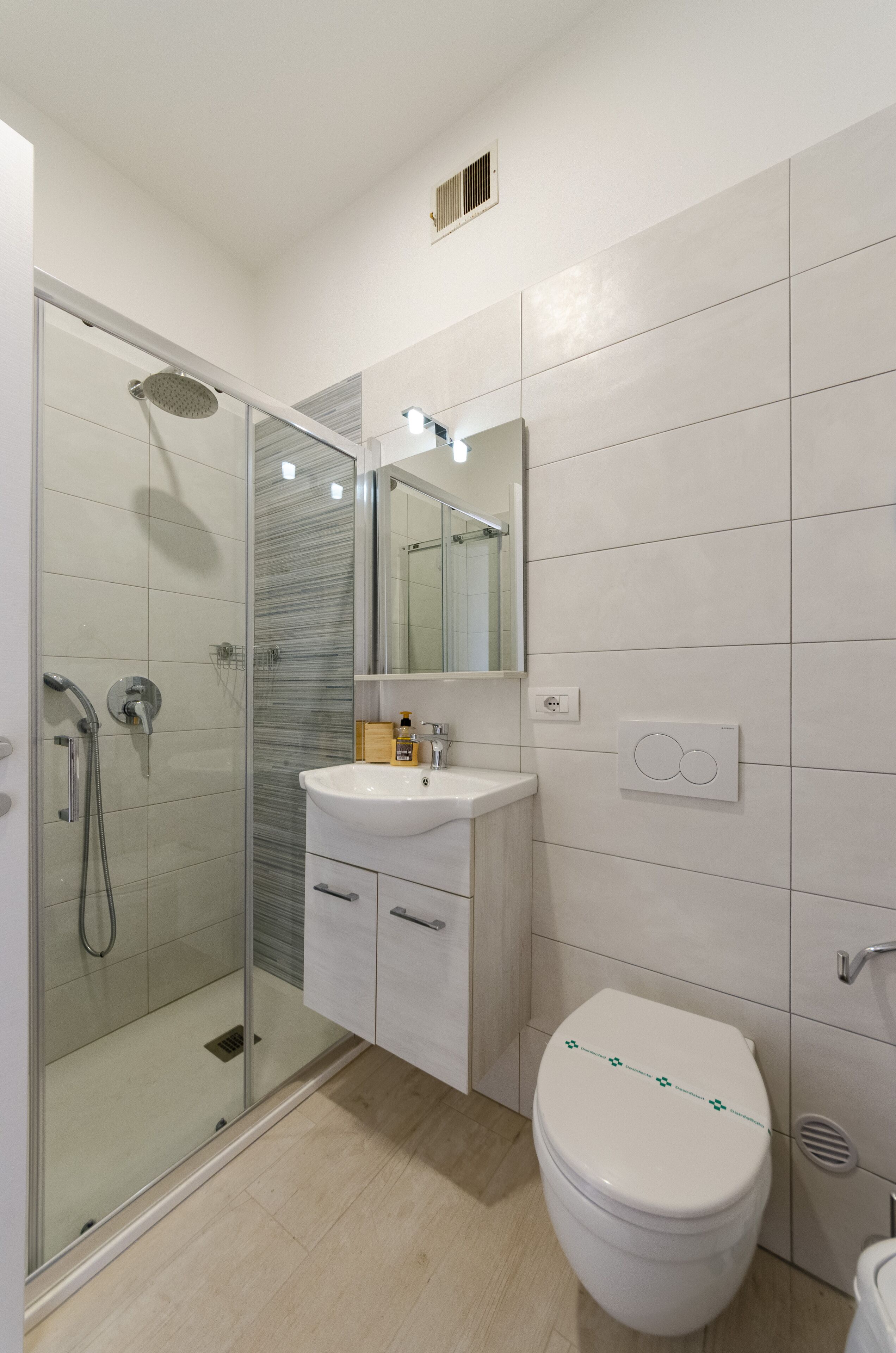 Un baño moderno con cabina de ducha de vidrio, un lavabo blanco y un inodoro.