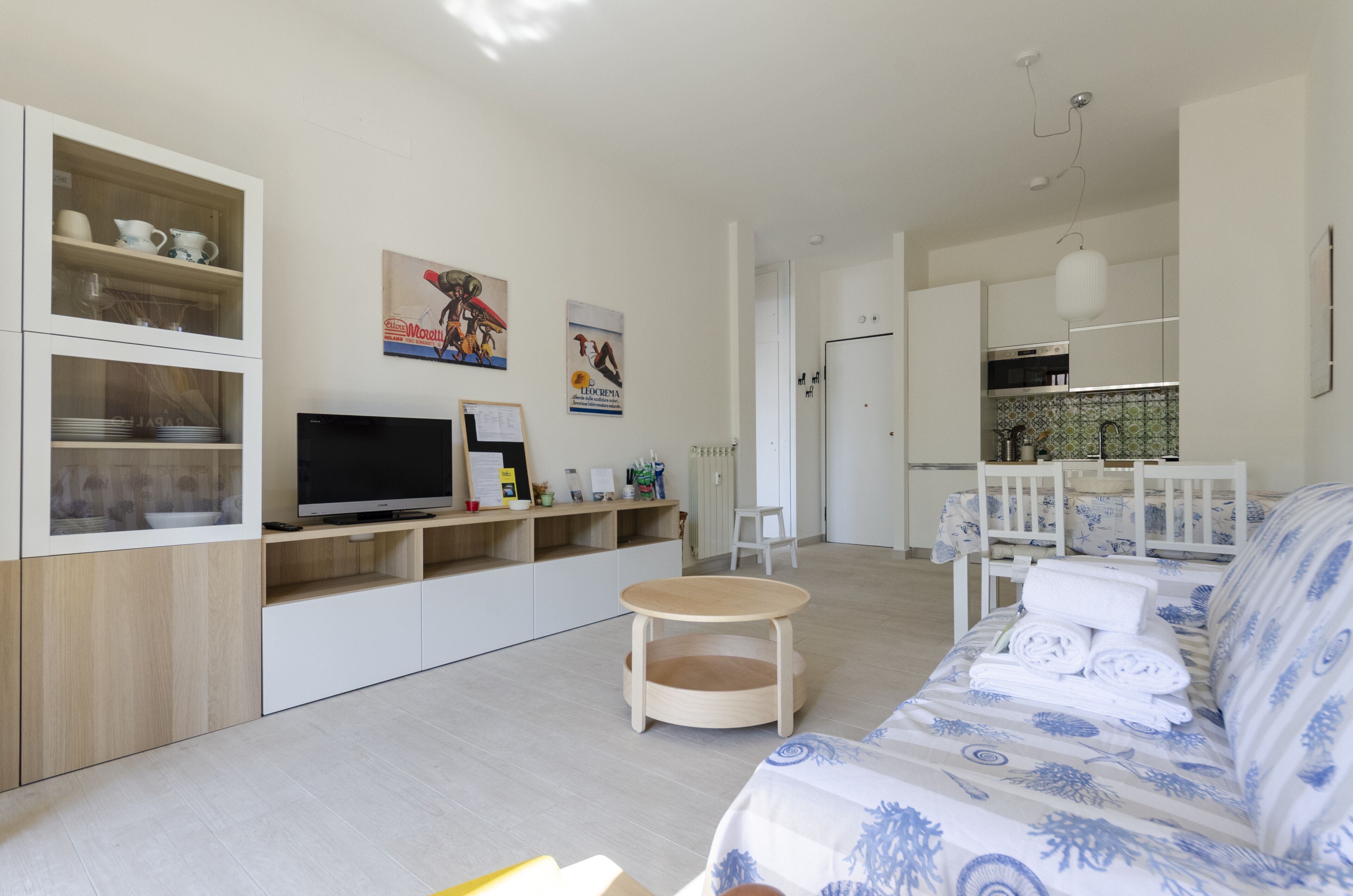 Un salon moderne avec un canapé, un téléviseur et des étagères en bois.
