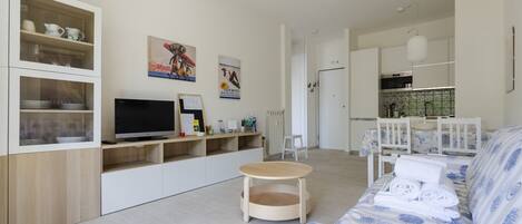 Un salon moderne avec un canapé, un téléviseur et des étagères en bois.