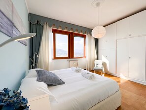 A bedroom with a large bed, a chair, a wardrobe, and a window with a view. - JOIVY Apartment In Rapallo W/Gulf View (Rapallo)