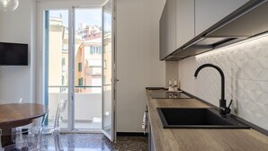 A modern kitchen with a large window, a dining area with a table and chairs, and a built-in sink. - JOIVY Two Steps From The Sea In Genoa (Genoa)